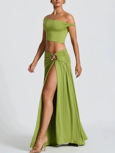 Detail of elegant gold floral metal buckle on a green high-slit maxi beach skirt