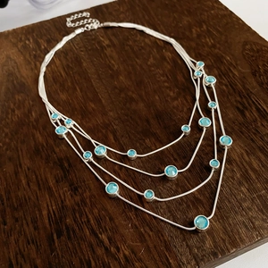 Detail showing silver multi-layered necklace with light blue round zircon gemstones
