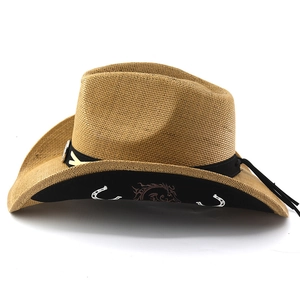Detail of straw cowboy hat featuring black decorative band and silver horseshoe ornament