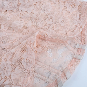 Gros plan sur un tissu en dentelle florale rose montrant les coutures et la texture
