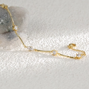 Elegant 18K gold plated brass bracelet with clear zircon stones on a textured surface