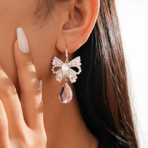 Close-up of bow earrings with pink zircon waterdrop pendants worn by a model
