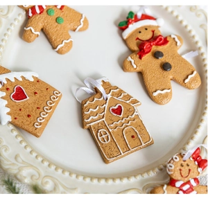 Detail shot of 3D gingerbread man and house ornaments with textured icing on a white plate