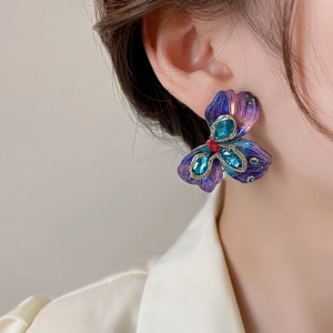 Close-up of vintage purple flower earring with blue gemstone and gold metal details