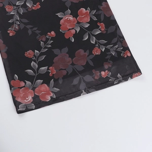 Détail du tissu en maille noire avec imprimés de roses rouges et finitions de l'ourlet