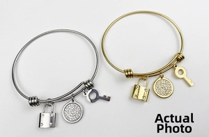 Detail of adjustable wire bracelets in gold and silver with lock, key and crystal charms