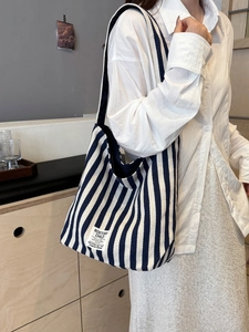 Blue and white striped canvas tote bag shown on model in a modern home setting