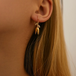Elegant 18K gold plated brass tulip pendant earrings worn by a model in a close-up view