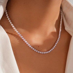 Close-up of lavender faux pearl beaded necklace worn on a white shirt collar for women