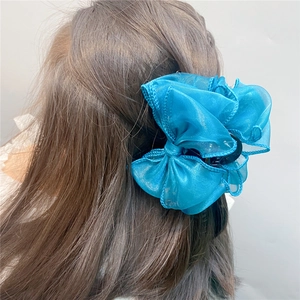 Rear view of a model wearing a large blue organza bow hair claw clip with pleated texture