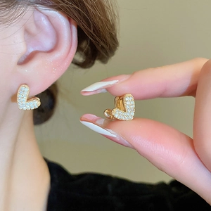 Détail des boucles d'oreilles cœur en zircon portées à l'oreille pour voir le style
