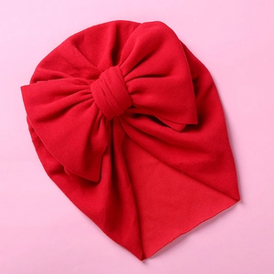 Detailed view of soft red knit baby turban hat featuring a large decorative bow