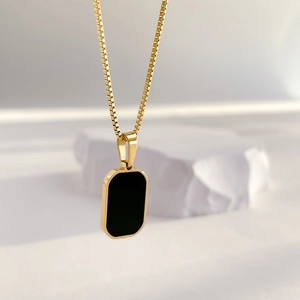 Detailed view of black onyx rectangular pendant on gold box chain with soft shadow