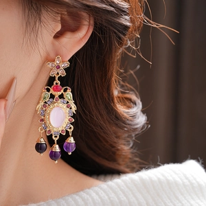 Detail of vintage palace style earring with colorful gems on model's ear