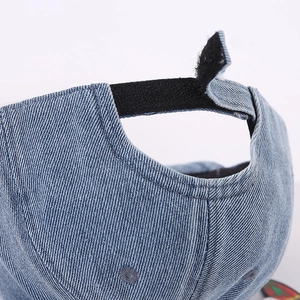 Détail de la sangle velcro noire réglable sur l'arrière de la casquette bébé denim