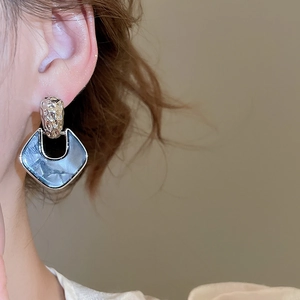 Close-up of a vintage geometric drop earring with silver hammered metal and dark blue acrylic