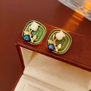 Macro detail of vintage green enamel square earrings with pearl flowers in a jewelry box