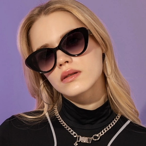 Close-up of black cat-eye sunglasses featuring purple gradient lenses on a fashion model