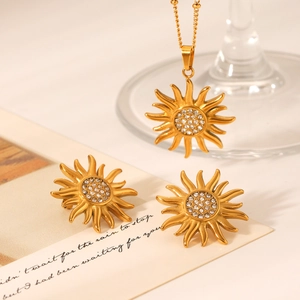 Golden sunflower necklace and earrings set with clear crystals on an aesthetic card