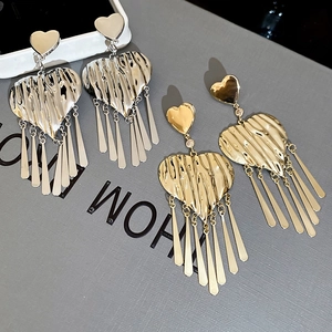 Detailed macro view of heart-shaped fringe earrings with wrinkled texture in gold and silver