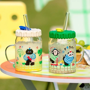 Close-up of glass mason jars with silicone lids and straws featuring animal illustrations