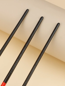 Detail of three nail art brushes featuring black wooden handles and red coated tips