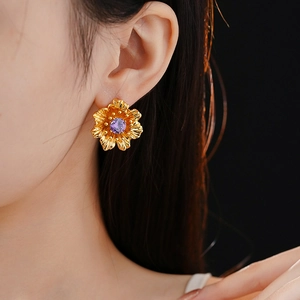 Close-up of golden flower earring with purple gemstone on ear for elegant vintage style