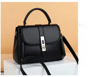 Detail view of black soft leather handbag with gold clasp and textured zip side design