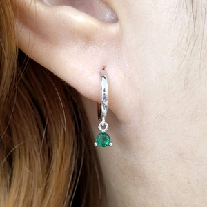 Close-up of 925 silver hoop earrings with a prong-set round green zircon pendant