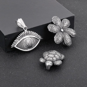 Detail of vintage silver turtle, flower, and evil eye pendants in textured stainless steel