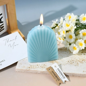 Detailansicht einer brennenden blauen Muschelkerze auf Marmor mit Etikett