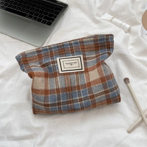 Detail view of plaid tweed cosmetic bag with Pleasant Time label on soft white linen cloth