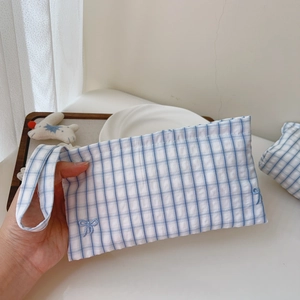 Detailed view of blue checkered cotton pouch with bow embroidery and wrist strap