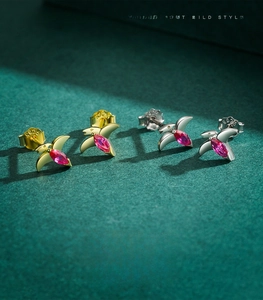 Détail macro de clous d'oreilles oiseaux en argent S925 avec zircon rose sur fond sombre