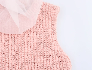 Close-up of pink knitted top featuring chunky weave and delicate light pink tulle at neckline