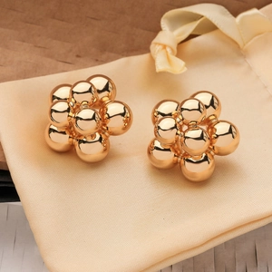 Gold-plated floral stud earrings in a beaded flower design on a beige pouch