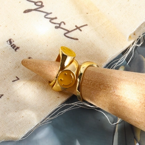 Anello con sigillo dorato minimalista con faccina sorridente e fede su supporto in legno