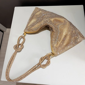 Macro shot of shimmering gold rhinestone handbag with a unique knotted handle design