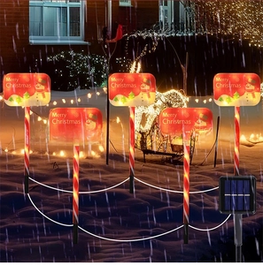 Solar Christmas candy cane stake lights with Merry Christmas snowman signs in snow