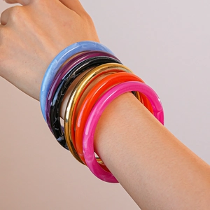 Gros plan de bracelets en résine acrylique colorée et anneau en métal doré au poignet