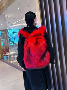 Detail eines großen flauschigen Rucksacks mit rot-schwarzem Farbverlauf aus Kunstpelz