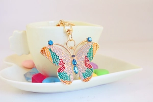Detail shot of a golden crystal butterfly keychain inside a white porcelain cup