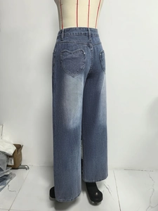 Detail view of double heart-shaped pockets on the back of vintage washed wide-leg jeans