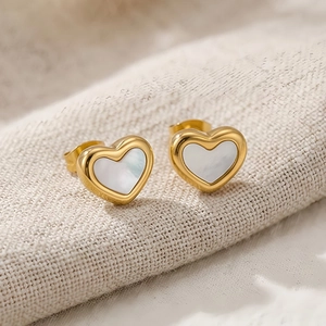 Dettaglio macro di orecchini a cuore placcati oro con intarsio in madreperla bianca