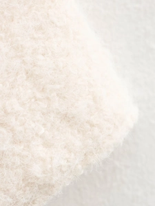 Close-up of soft off-white plush knit fabric showing premium mohair wool texture