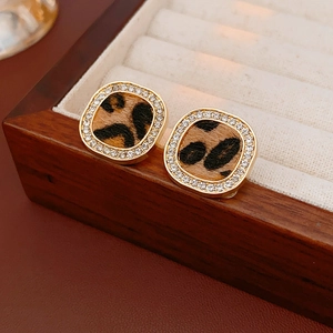Macro view of gold-plated square leopard print earrings with sparkling crystal halo