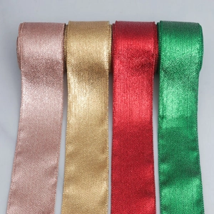 Dettaglio di quattro nastri glitterati metallici in oro rosa, oro, rosso e verde per regali