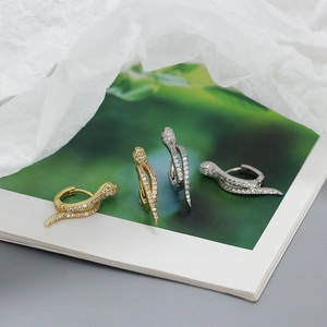Detailed view of snake-shaped gold and silver earrings with micro-inlaid diamonds