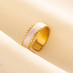 Détail d'une bague ouverte dorée avec incrustation de marbre blanc et perles