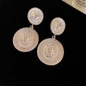 Vintage silver lion head coin earrings with tiered textured borders on black background